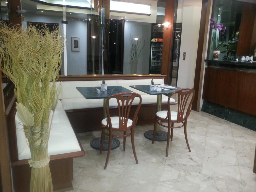 A dining area with a bench and two tables, surrounded by chairs.