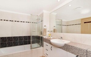 Un bagno moderno con doccia vetrata, lavandino bianco e uno specchio grande.