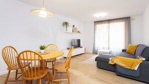 Un soggiorno moderno con zona pranzo, divano e televisore.