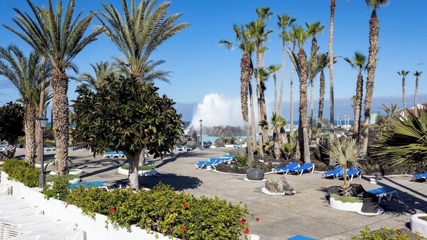 Un resort con palme, poltrone a sdraio e vista sull'oceano.