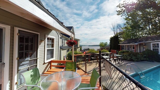 A residential deck with outdoor furniture, a pool, and a view of the water. - The Lakeview Cottage 9 (Laconia)