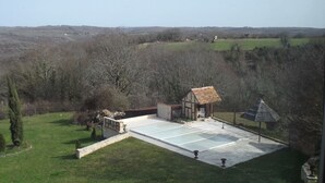 Un amplio espacio al aire libre con una piscina, una pequeña estructura de madera y un pabellón.