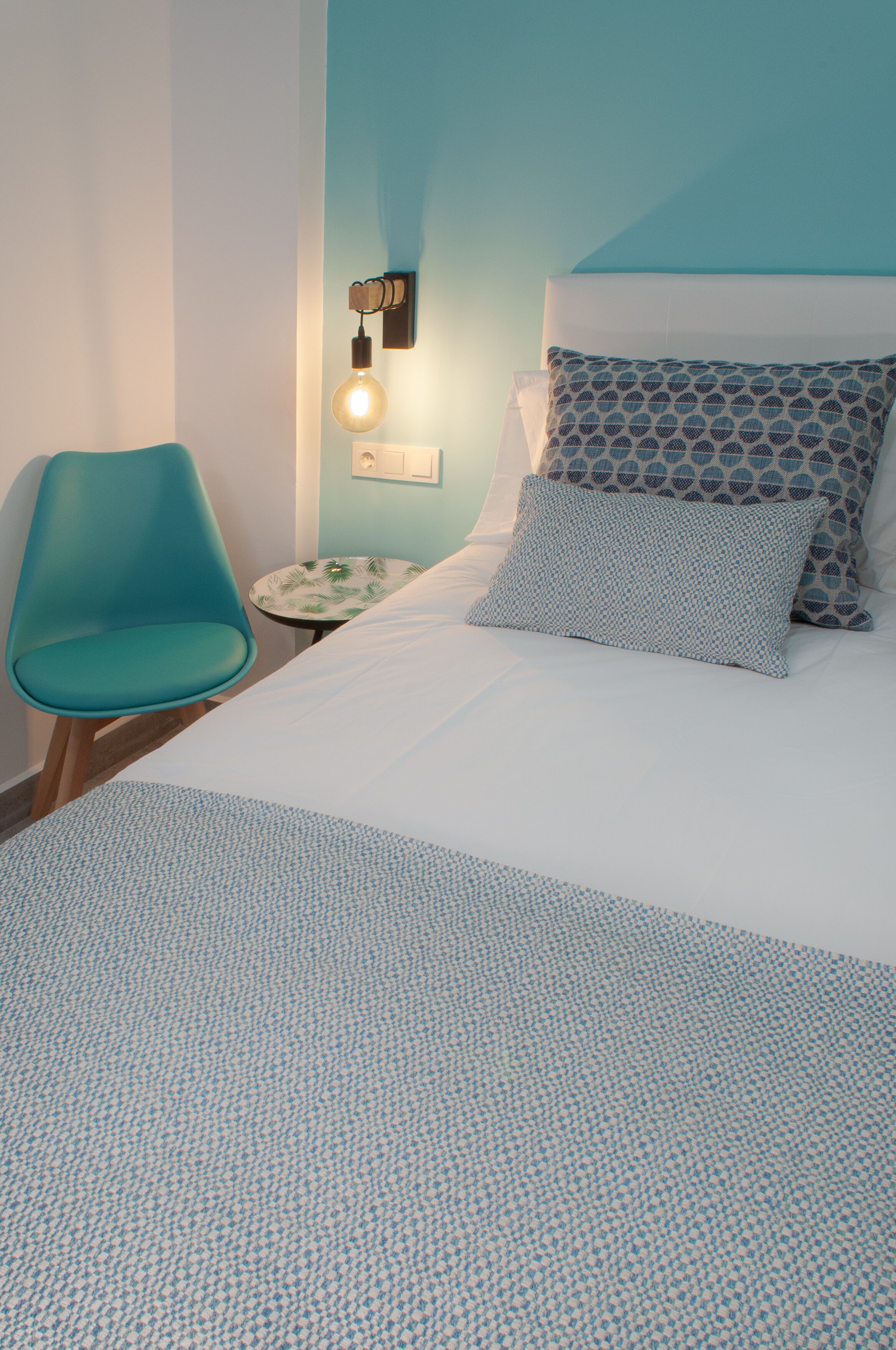 Une chambre bien rangée, avec un lit, une chaise et une petite table.
