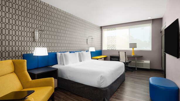 Une chambre d’hôtel équipée d’un lit, d’un bureau, d’une chaise, d’un canapé et d’une télévision.