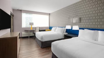 Une chambre d’hôtel avec deux lits, un bureau, une chaise, une télévision et un mur décoré d’un motif.
