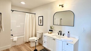 Ein modernes Badezimmer mit Dusche, Toilette, Waschbecken und Spiegel.