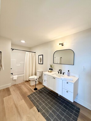 Ein modernes Badezimmer mit Dusche, Toilette, Waschbecken und Spiegel.