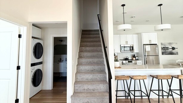 Ein modernes Interieur mit einer Treppe, die zu einer Küche, einem Waschraum und einer Bar mit Hockern führt.