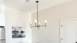 Ein Essbereich mit Holztisch, weißen Stühlen, einer Kristallleuchtre und einem Wandbild.