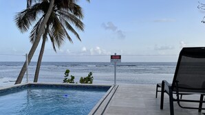Uma piscina com vista para o oceano, uma cadeira e uma placa com a inscrição 'PELIGRO'.