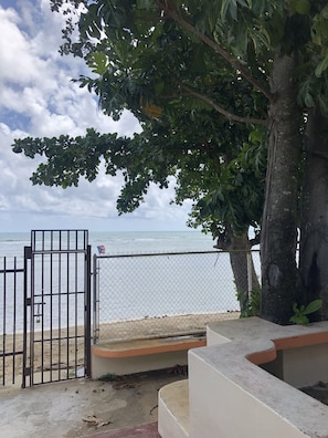 Enjoy stunning ocean views from this beachfront property, featuring an entrance and shaded seating area.
