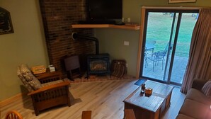 A cozy living room with a fireplace, a sofa, a coffee table, and a television. - Nice Condo At Attitash Mountain Village, Close to Storyland, Location! (Bartlett)