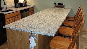 A kitchen with wooden cabinets, a granite countertop, a coffee maker, and a fire extinguisher. - Nice Condo At Attitash Mountain Village, Close to Storyland, Location! (Bartlett)