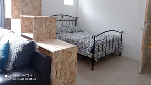 Ein Schlafzimmer mit Bett, Schreibtisch und Stuhl. Ein Fenster bietet Blick ins Freie.
