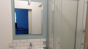 Ein Badezimmer mit einem weißen Waschbecken, einem Spiegel und einer Dusche mit Glastrennwand.