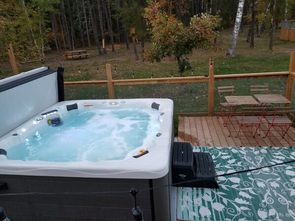 Ett bubbelbad på ett trädäck med utsikt över ett skogsområde.