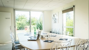 A conference room with a large table, chairs, a laptop, and a projector.