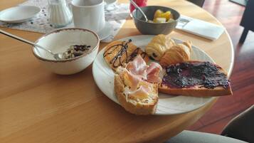 Een ontbijtsetting met een bord toast, croissants en een schaal fruit.