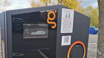 Eine schwarze Ladestation für Elektrofahrzeuge mit einem QR-Code und Gebrauchsanweisung.