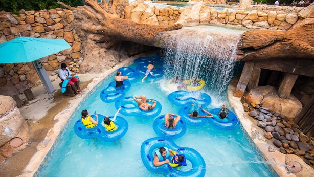 A water park with a pool, inflatable rings, and a waterfall.