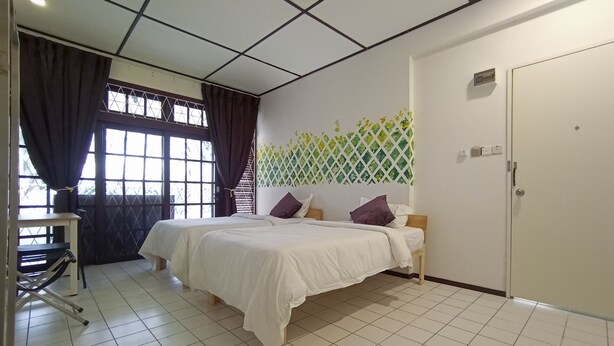 Een hotelkamer met twee bedden, een bureau en een raam met gordijnen.