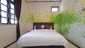 Een hotelkamer met een bed, een raam met gordijnen en een wand met een bloemenmuur.