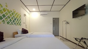 Een hotelkamer met twee bedden, een televisie, een airconditioning en een muur met een groen rasterontwerp.