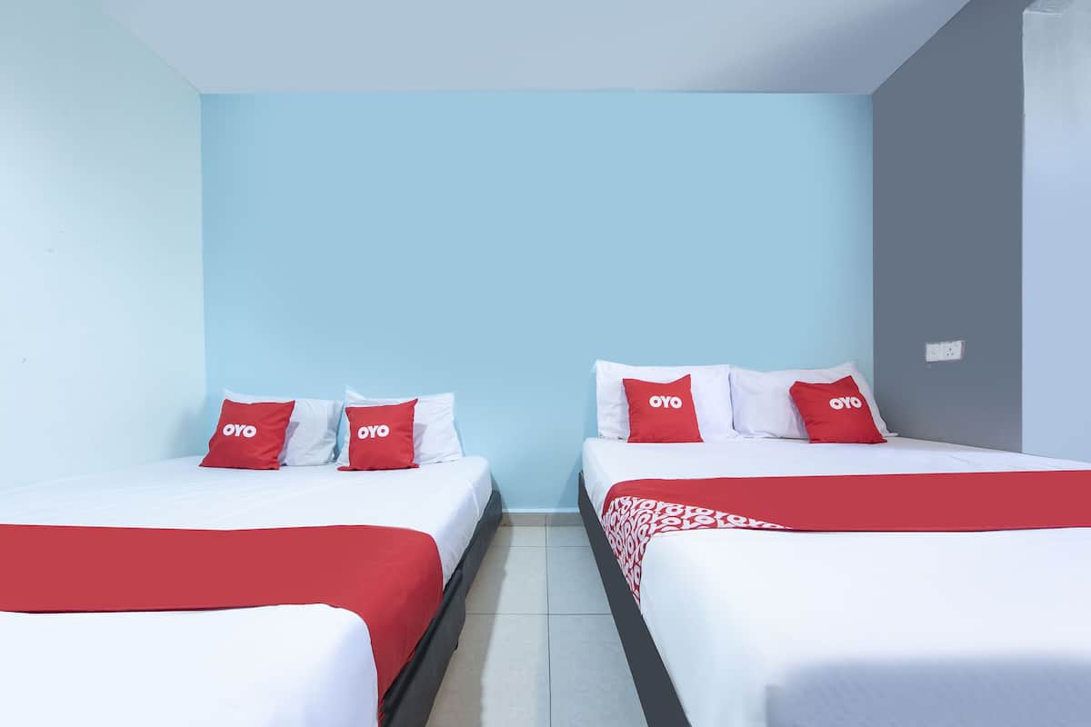 A hotel room with two beds, each with white bedding and red accents, including pillows and a blanket.