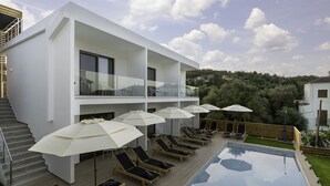 A modern building with a pool, sun loungers, and umbrellas. - Sigma Luxury Rooms (Igoumenitsa)