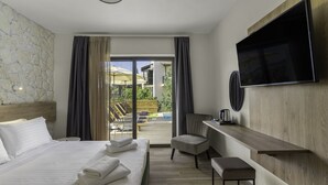 A hotel room with a bed, a desk, a chair, a TV, and a view of the outdoor area. - Sigma Luxury Rooms (Igoumenitsa)