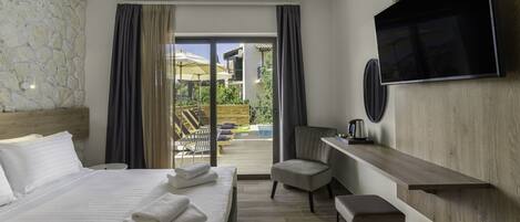 Habitación de hotel con cama, escritorio, silla, televisión y vistas al exterior.