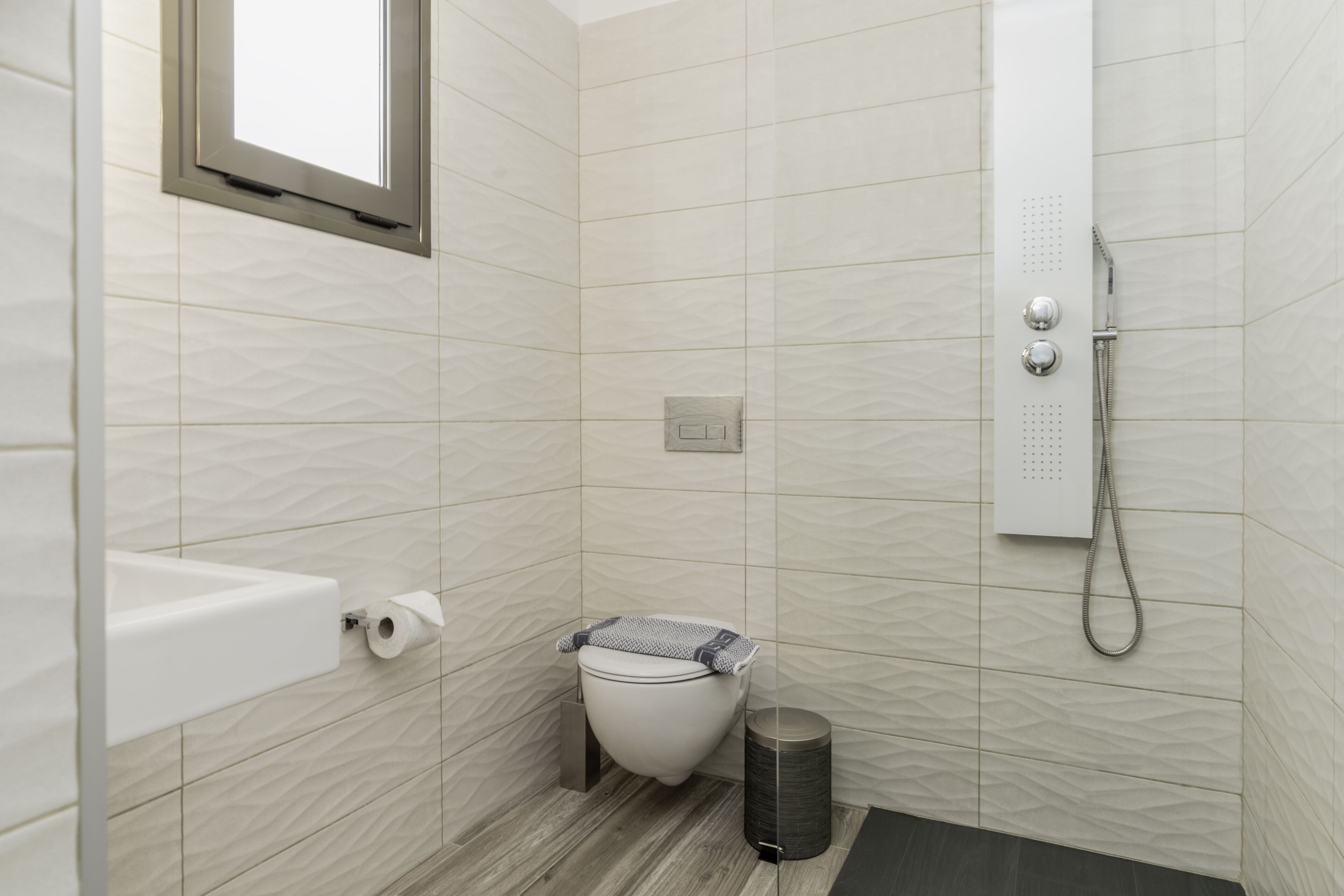 A small bathroom with a toilet, a bidet, a trash can, and a shower.