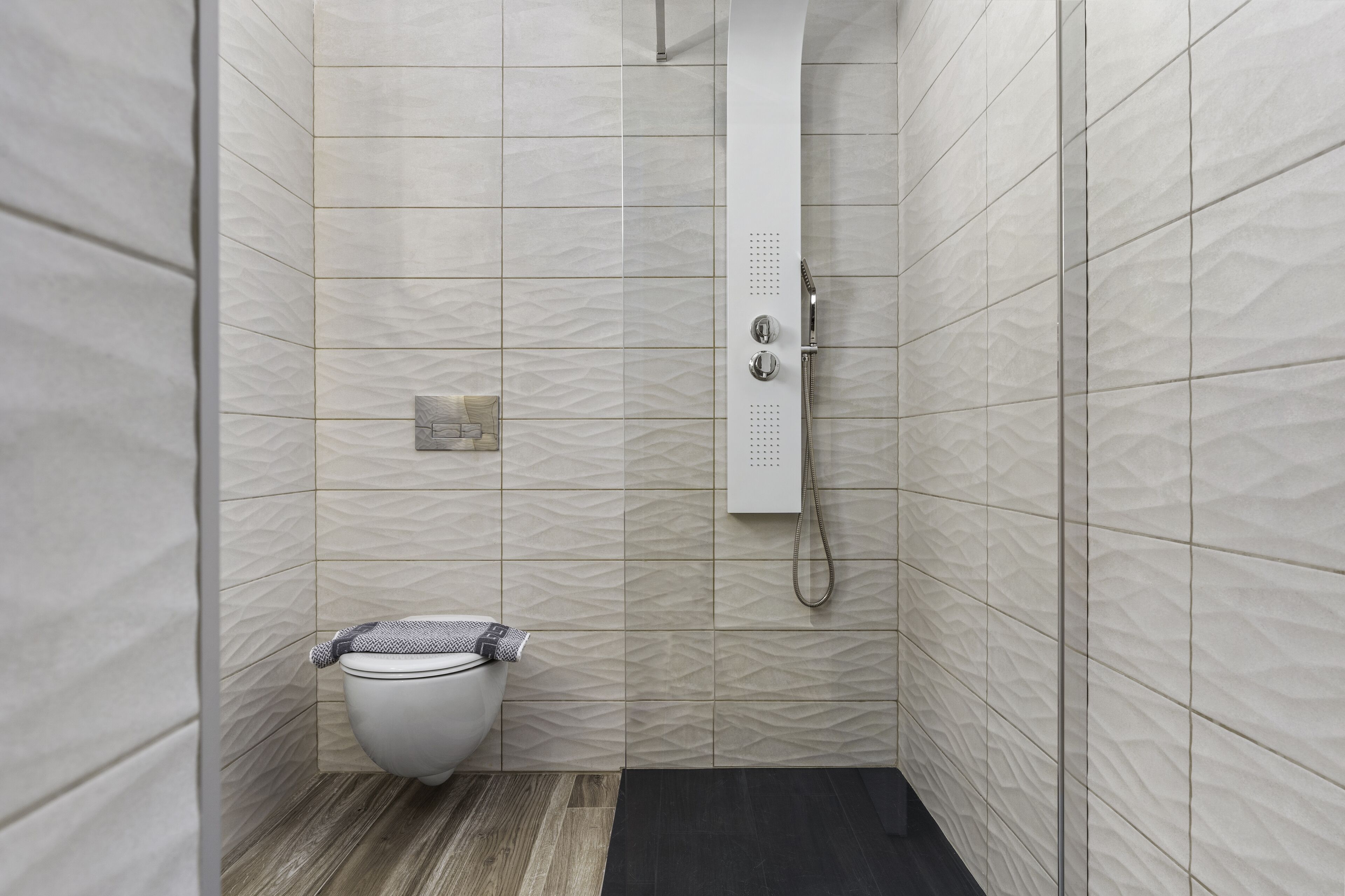 Een kleine, moderne badkamer met toilet, douche en handdoekhouder.