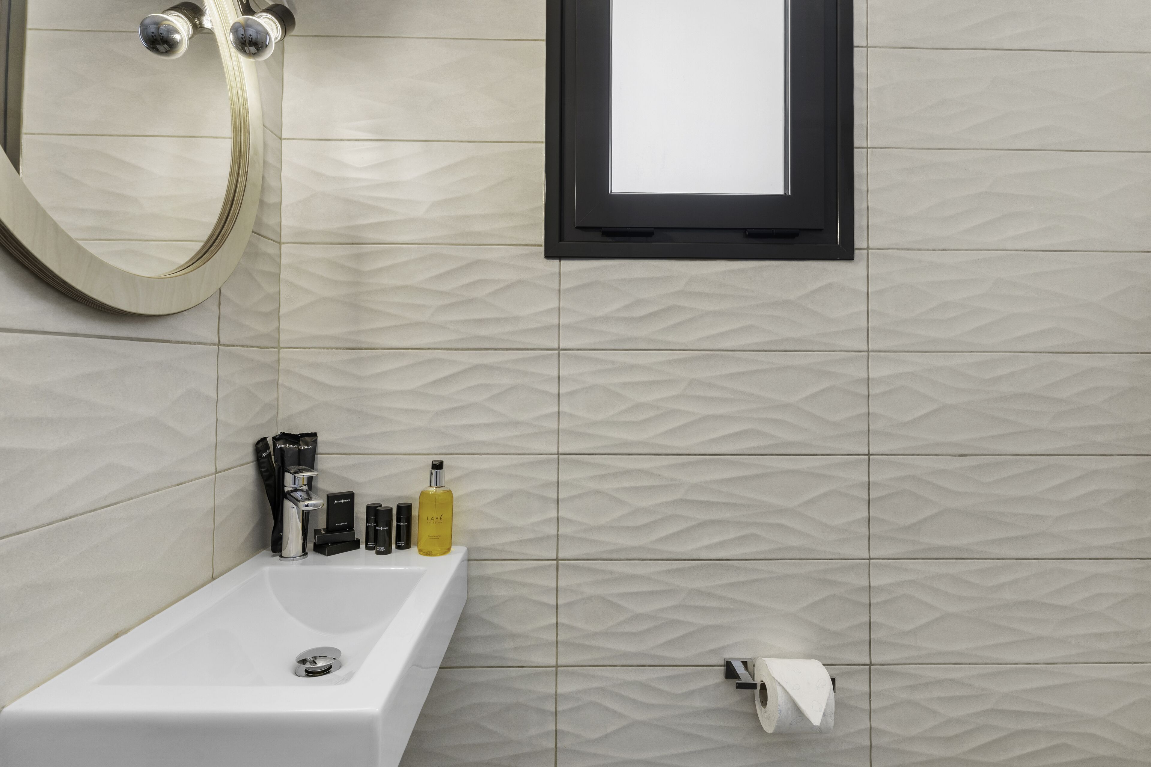 Ein Badezimmer mit einer weißen Badewanne, einem Handtuchhalter und Pflegeprodukten am Rand.