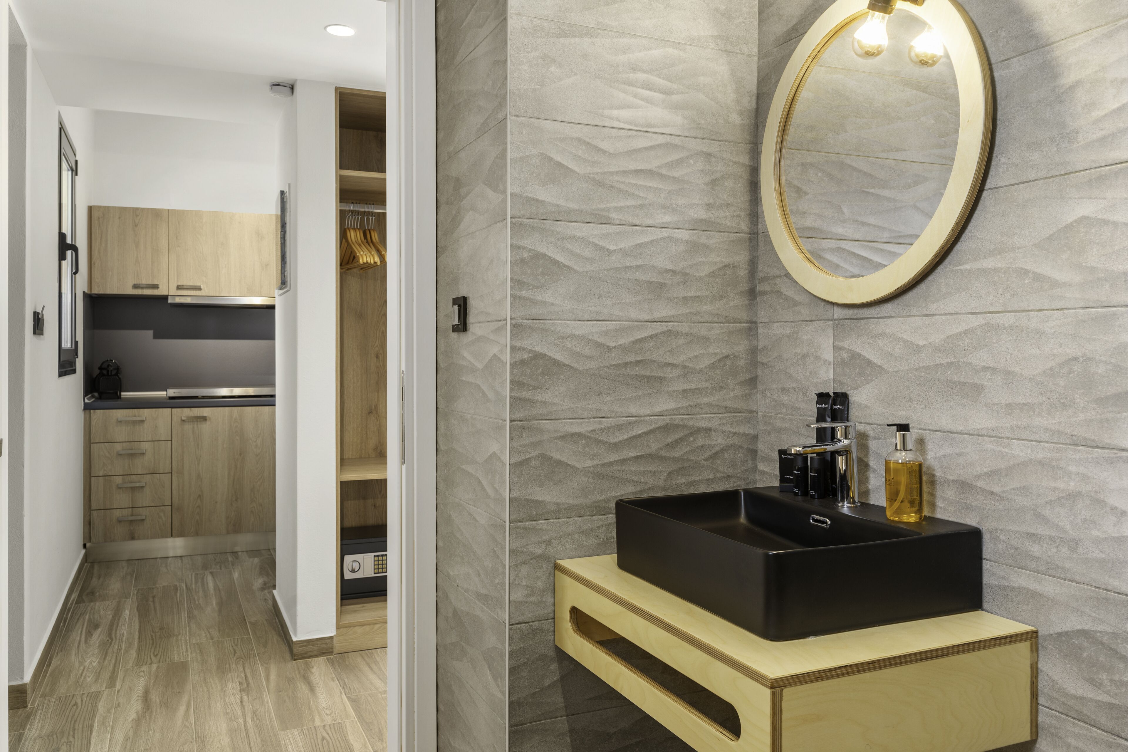 A modern bathroom with a black sink, wooden vanity, and a textured wall.