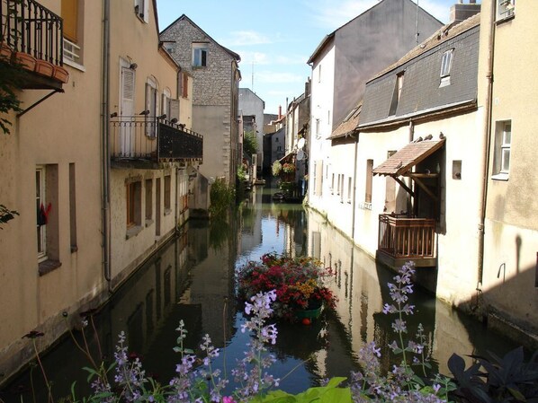 A narrow canal flanked by buildings with balconies and flower pots.