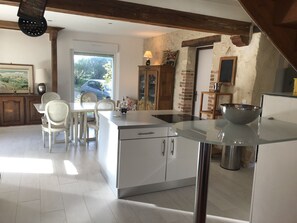 Enjoy meals in this kitchen with a central island, white cabinetry, and a glass-top table.