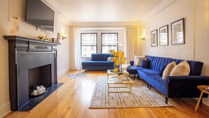 A living room with a fireplace, blue sofa, and a flat-screen TV mounted on the wall. - Guild #2 | Gold Coast Mag Mile Best Location (Chicago)