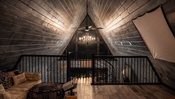 A cozy attic room with a wooden floor, a black railing, a chandelier, and a staircase. - Ultimate Romantic Couples Getaway in Wine Country (Dobson)