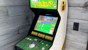 A 3D golf arcade game machine with a screen displaying a golf game, control buttons, and a branded logo. - Ultimate Romantic Couples Getaway in Wine Country (Dobson)
