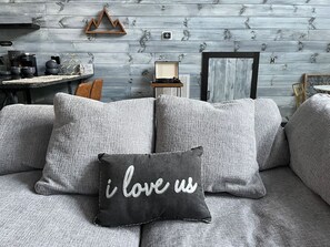 A gray sofa with multiple cushions and a black pillow with white text.