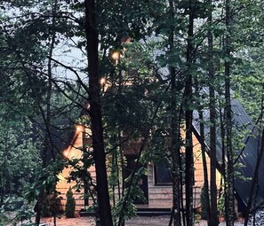 A cabin surrounded by trees with a visible entrance and a sloped roof.