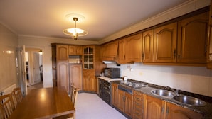 A kitchen with wooden cabinets, a granite countertop, a built-in microwave, and a double sink. - Vieiro Verde 2 Rustic (Vieiro)