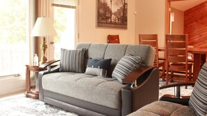 Un salon avec un canapé, une lampe, une table à manger et des chaises.