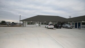 A building with a flat roof and large windows. There are several cars parked in front. - Edna Star Motel & Laundry (Edna)
