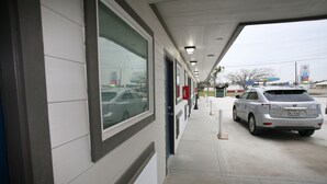 A building with a covered walkway and a parked car. - Edna Star Motel & Laundry (Edna)