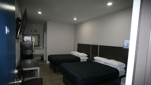 A hotel room with two beds, a desk, a chair, a TV, and a microwave. - Edna Star Motel & Laundry (Edna)