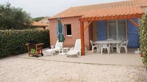 A covered patio with outdoor seating, a small table, and a cart with items.