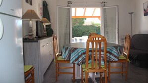 A compact kitchen with a dining area, a large window, and a view of greenery outside.