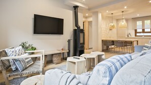 Un salon moderne doté d’une cheminée, d’un téléviseur à écran plat et d’un coin repas avec des chaises et une table.